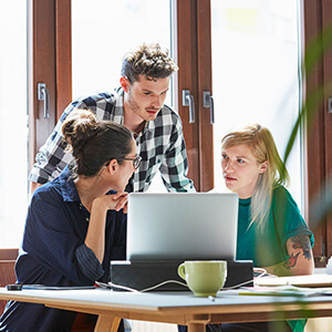 three people grouped around laptop