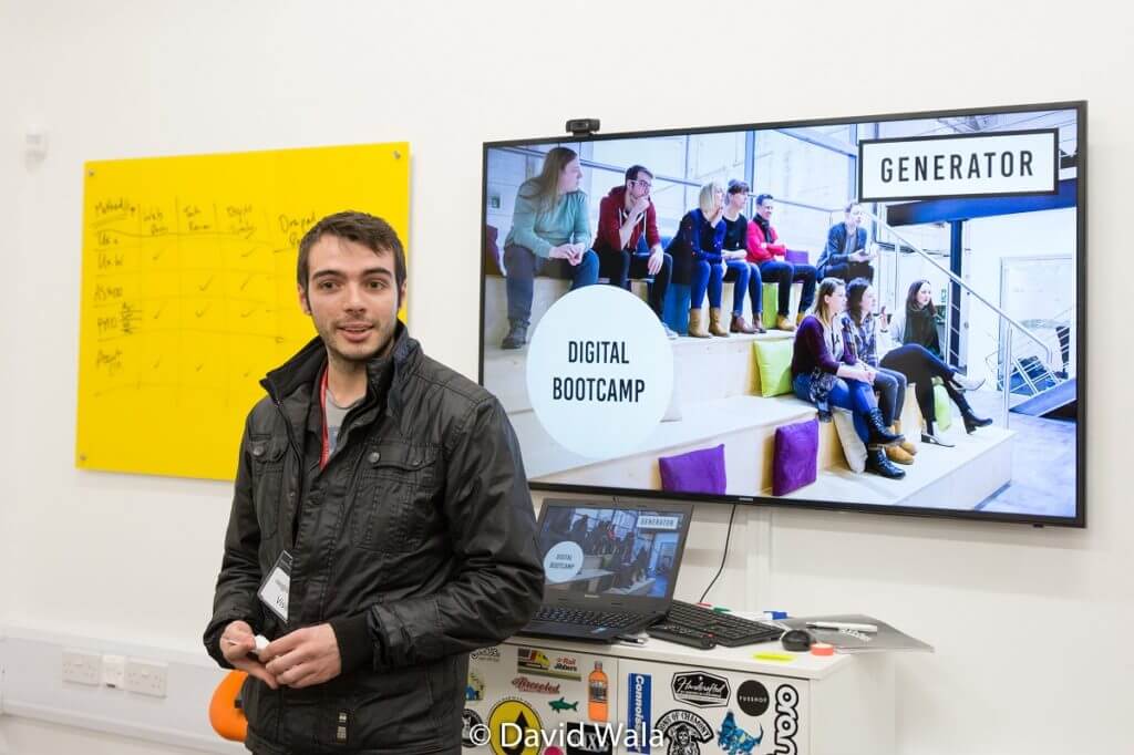 Man stood in front of tv screen with an image of Digital Bootcamp