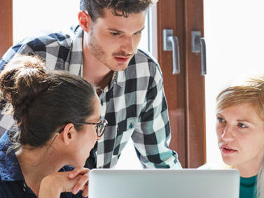 stock image of three people working around a computer