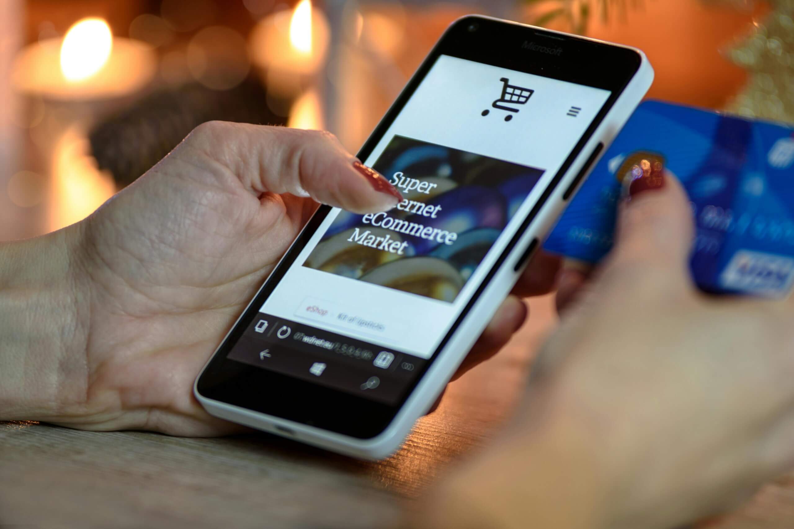 Person Using Black And White Smartphone and Holding Blue Card.
